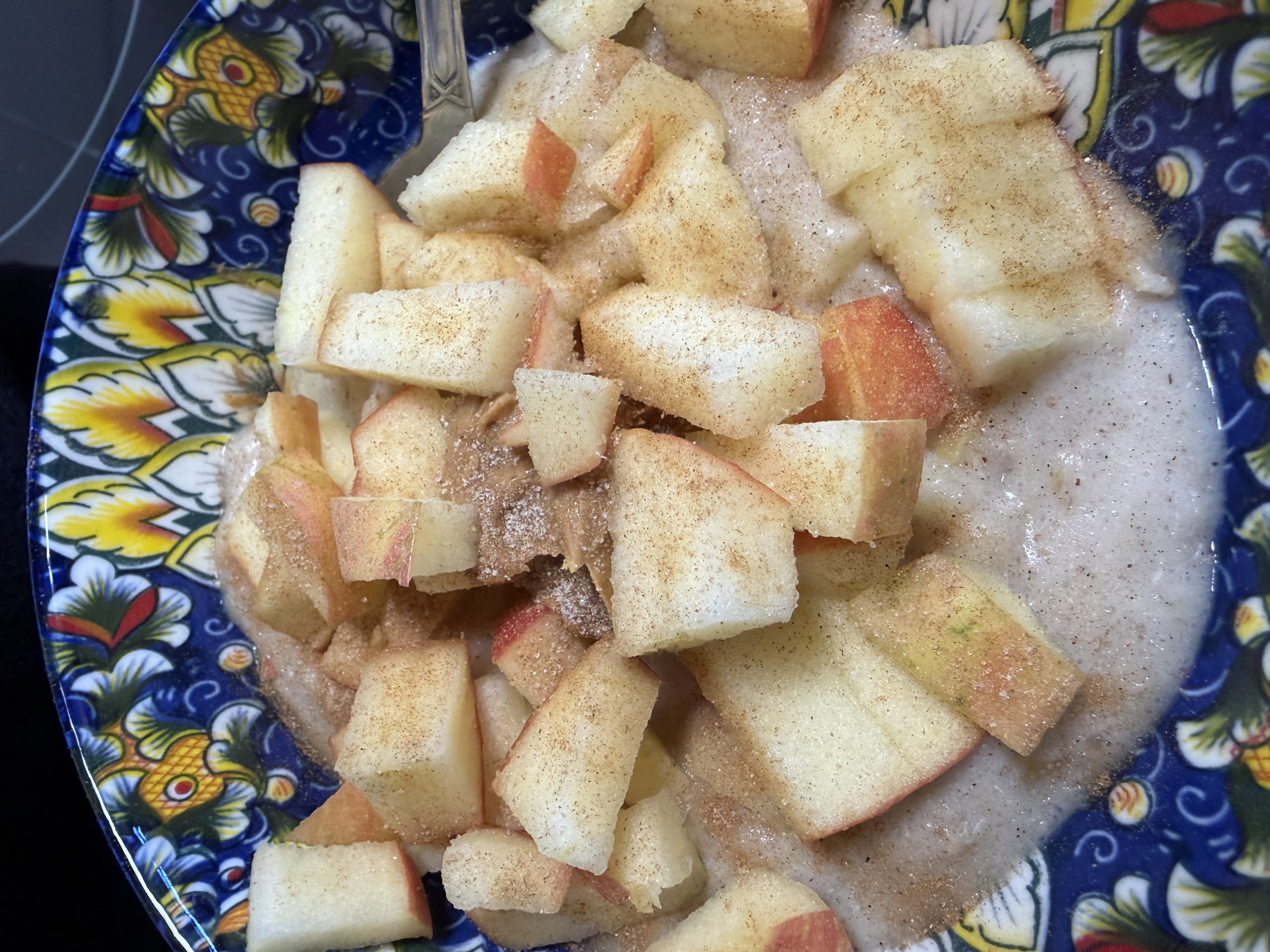 A bowl of creamy oatmeal loaded with diced fresh apple chunks dusted with cinnamon sugar